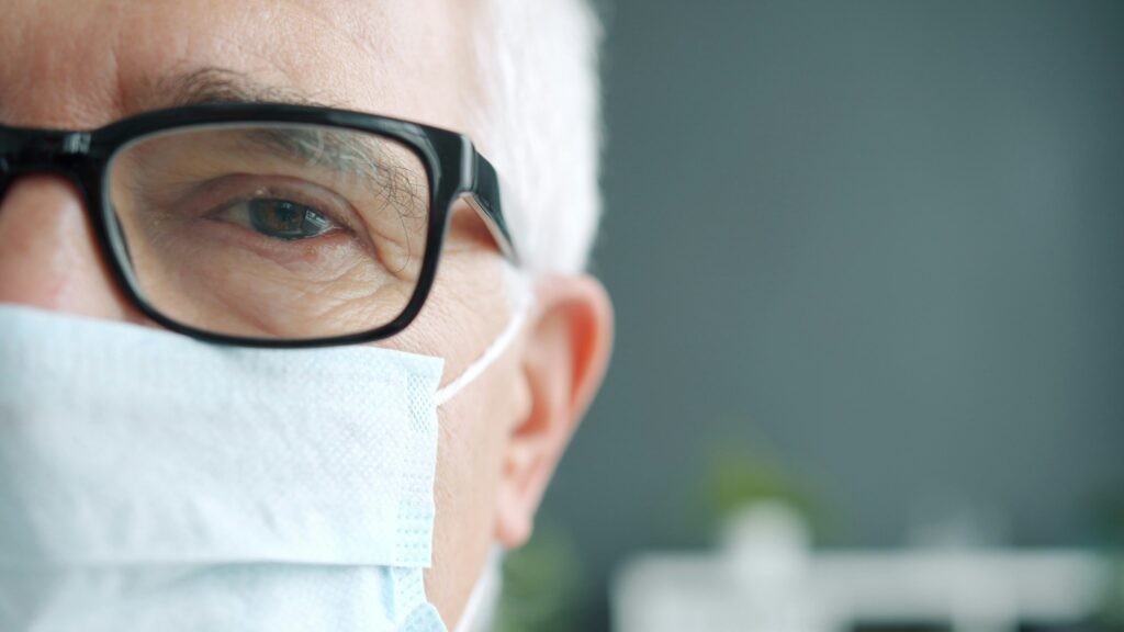 Senior man wearing a medical mask in a hospital setting during the COVID era