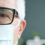 Senior man wearing a medical mask in a hospital setting during the COVID era